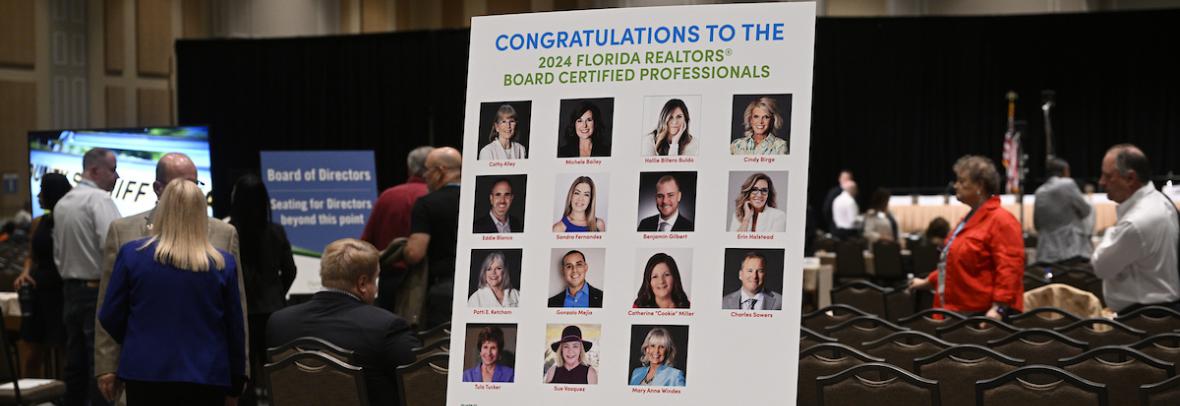 Realtors at Board of Directors meeting with congrats poster of new Board Certified Professionals in front